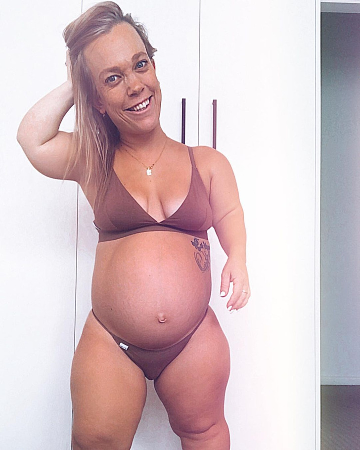 Woman with dwarfism wearing a brown bikini showing her pregnant belly.